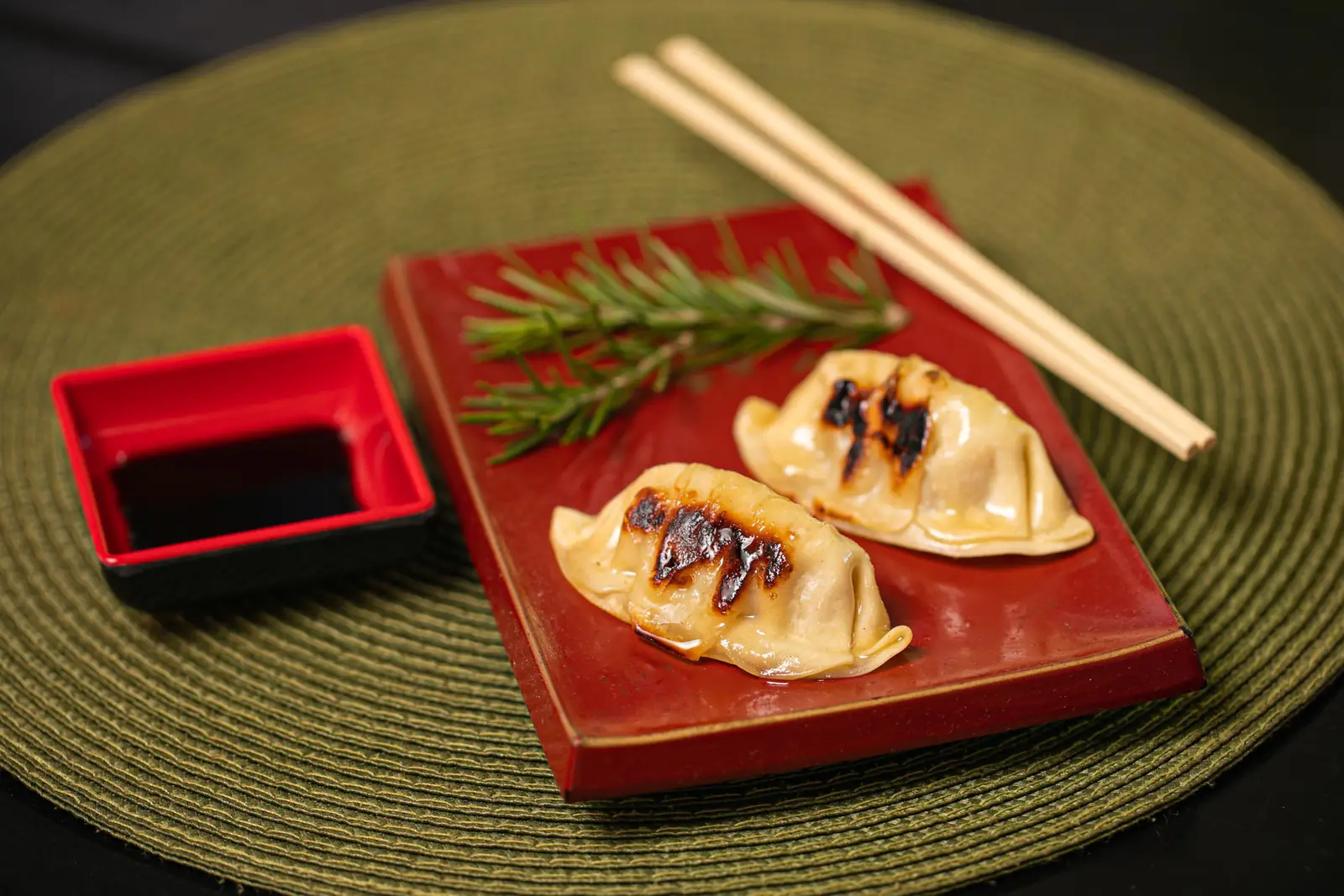 赤い角皿に盛った焼き餃子と小皿の醤油、箸（イメージ写真）